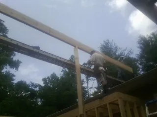 Carpenter setting a ridge beam over a new addition frame — Ice Dam Removal by Roofing Brothers in Pinecliffe
