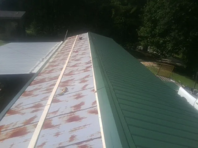 Old rusted panels beside newly installed green metal roofing — Wind Damage Roof Repair by Roofing Brothers in Pinecliffe