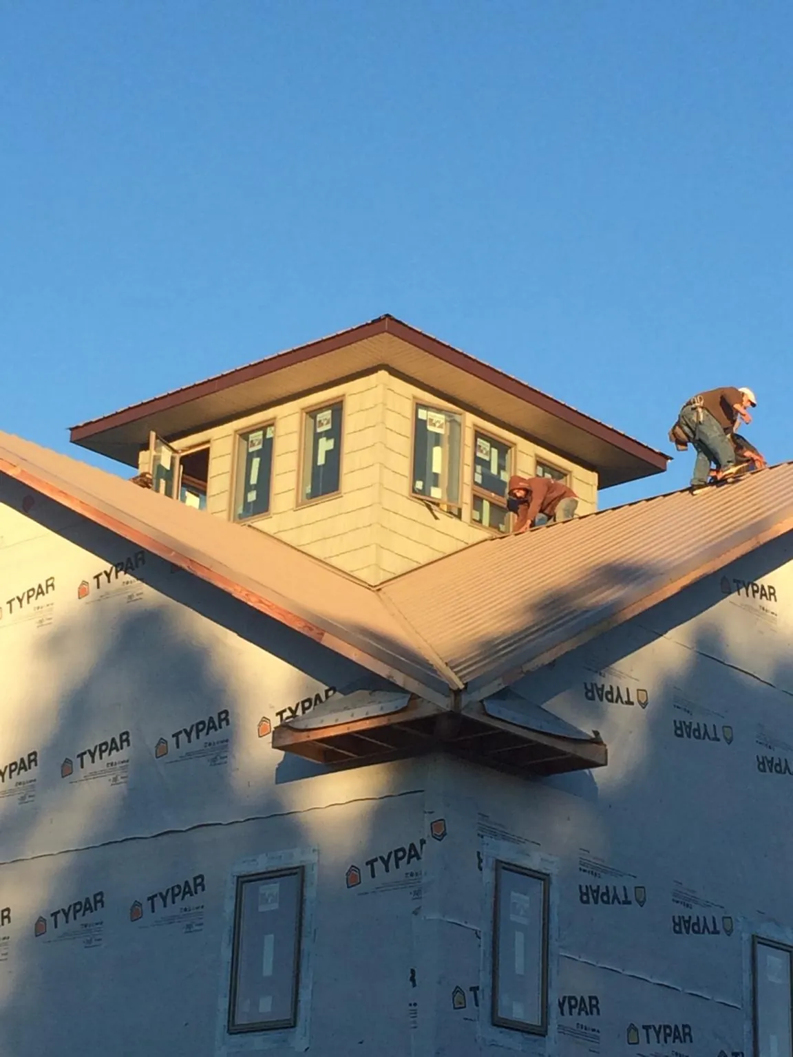 Roofers working around a rooftop cupola on a new metal roof at sunset — Roof Waterproofing in Pinecliffe by Roofing Brothers
